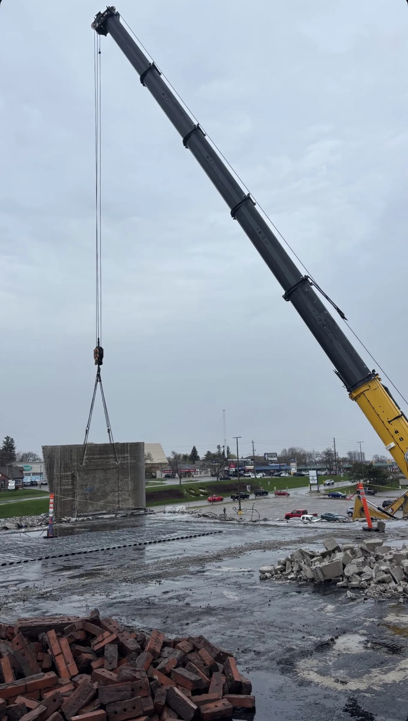 Crane lifting a concrete section clear of a demolition site
