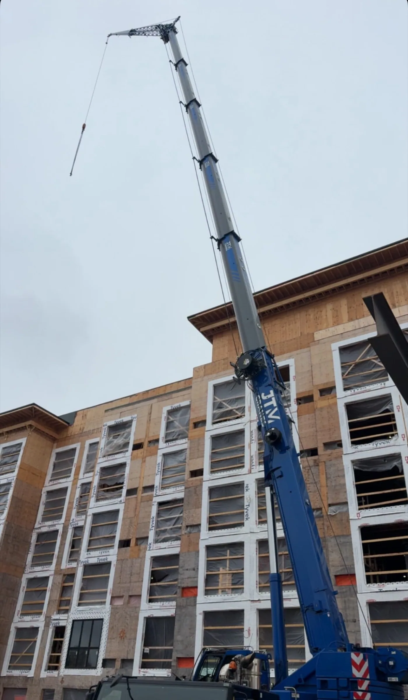 Blue all terrain crane working at a mid-rise building under construction