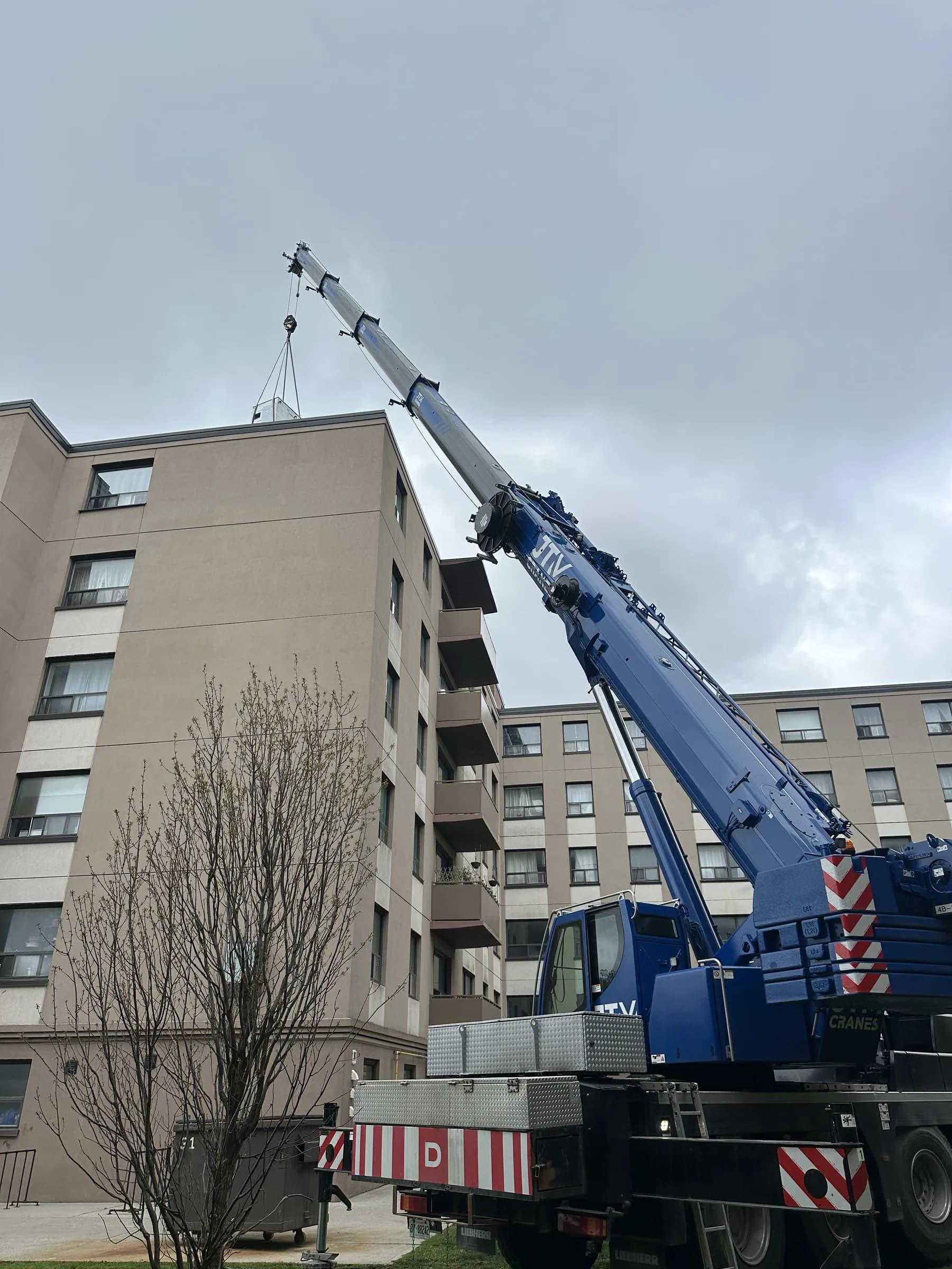 Crane working beside an apartment building on a residential street