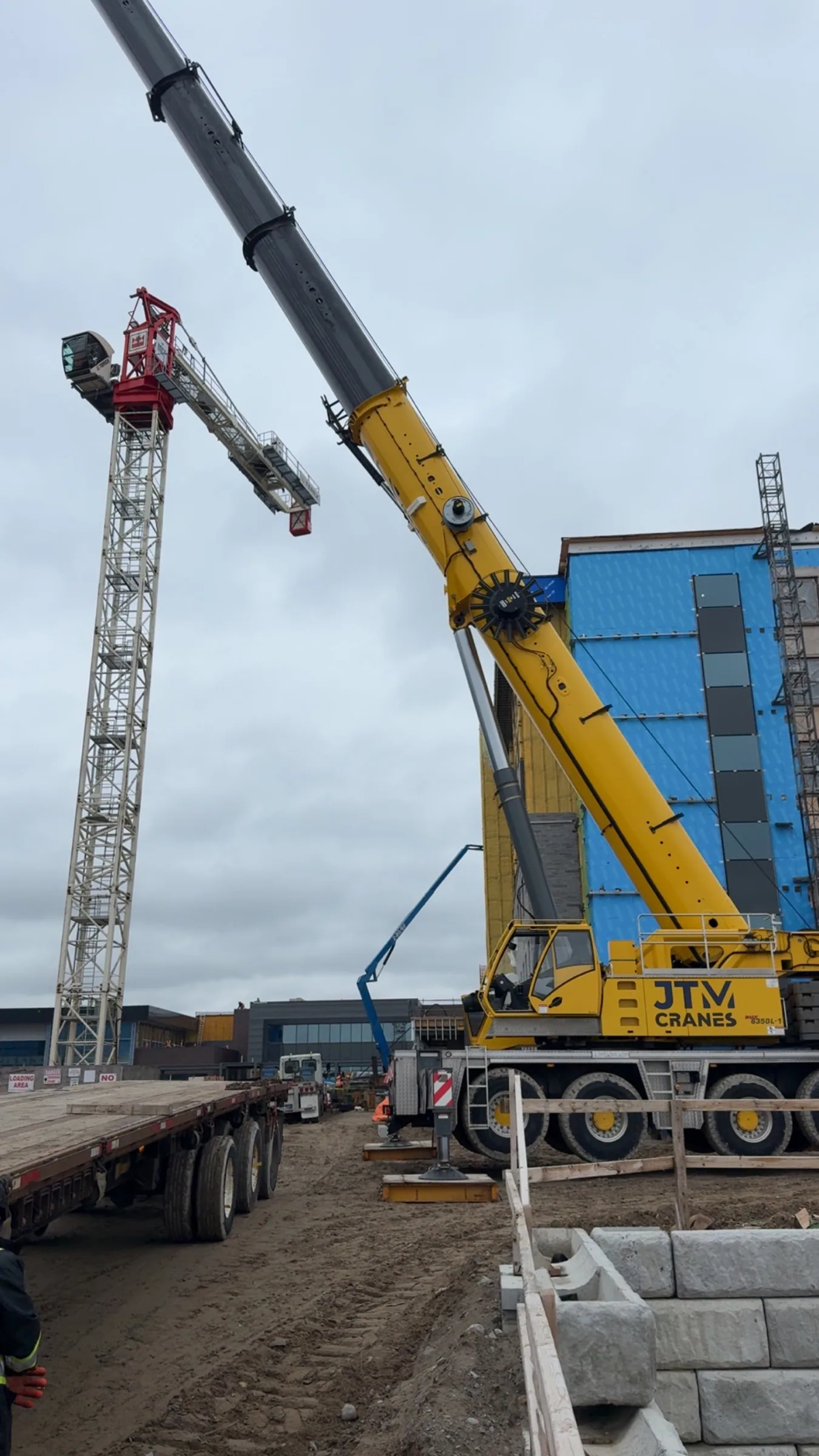 JTM Cranes crane working alongside a hoist tower at a steel and curtain wall install
