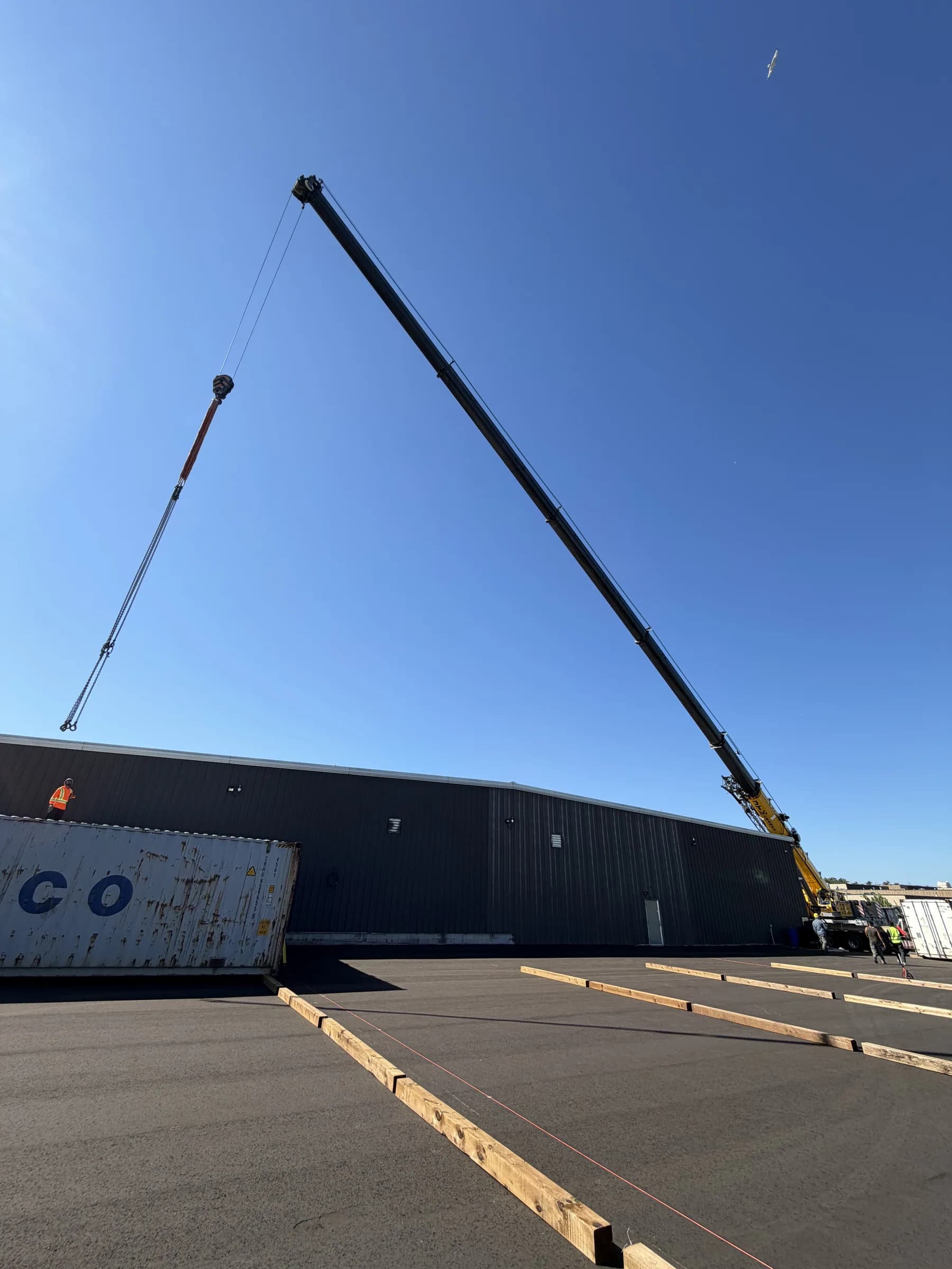 JTM Cranes mobile crane reaching across a warehouse roof on a clear day